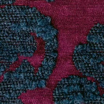 Burgundy and teal-blue fabric texture, woven base with looped motifs, labeled “egoitaliano kosmo blucle 1920”, matte finish, close-up view.